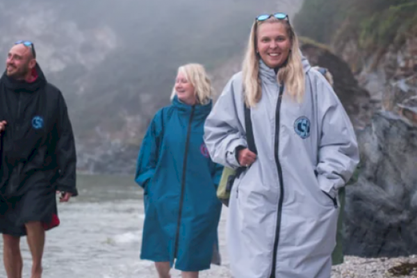 Blonde woman wearing a Cornwall Swim Co Dry Robe with two others behind her