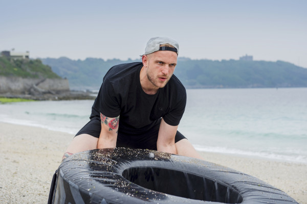 Man using tyre to exercise on Gyllyngvase Beach